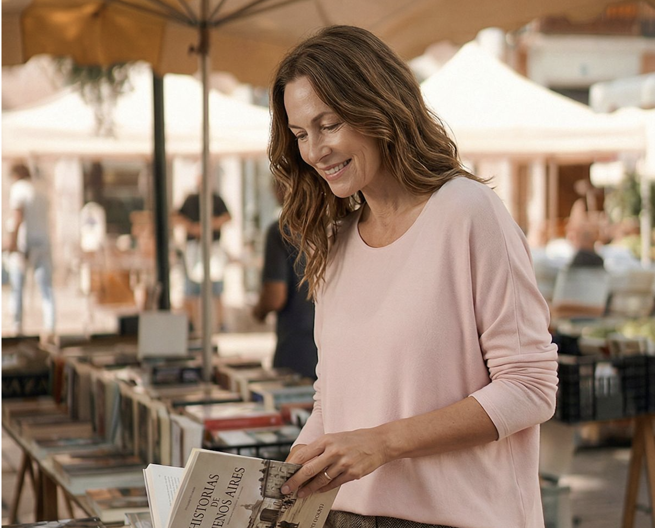 Modelo con sweater rosa recorriendo una feria de libros al aire libre